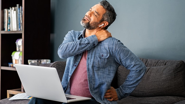 ﻿﻿Man sitting on couch with neck pain