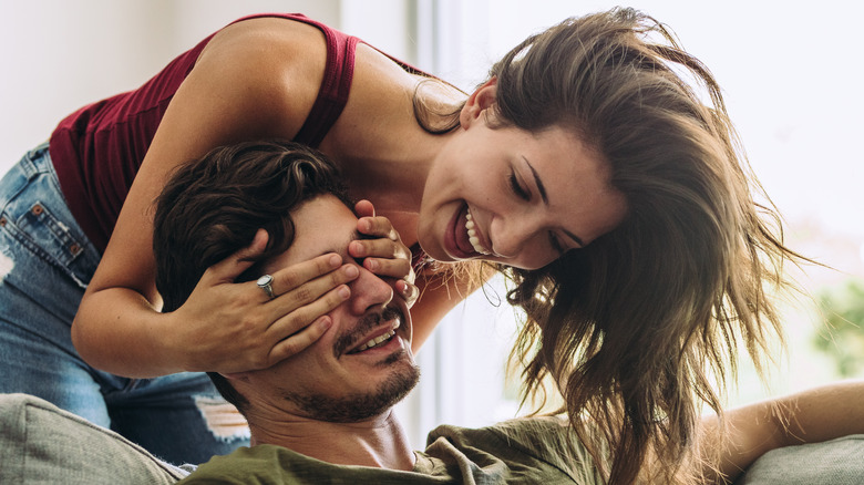 Laughing woman covering man's eyes