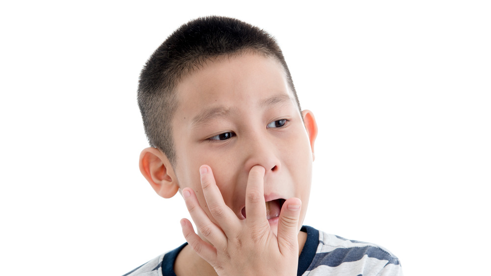 Young boy picking his nose with all white background 