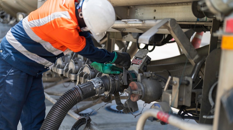 Safety worker in hard hat working on a gasoline delivery truck