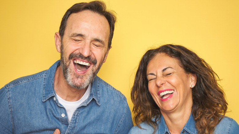 Couple laughing on yellow background