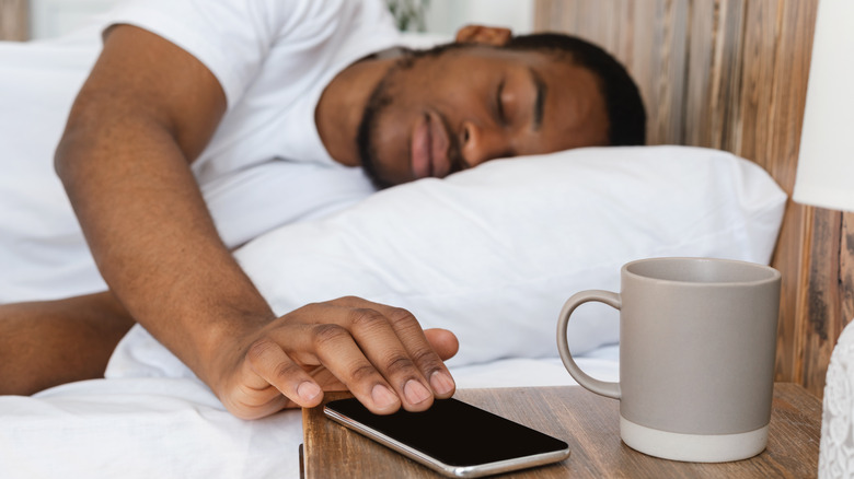 Man reaching out to turn off alarm on phone