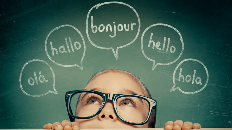Young child wearing glasses with speech bubbles above their head containing the word "hello" in different languages