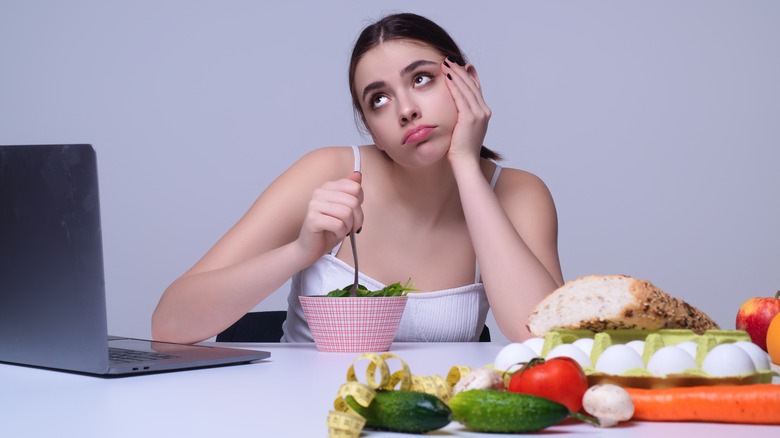 woman rolling her eyes while eating diet food