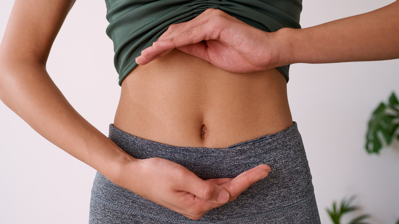 Woman's hands encircling stomach