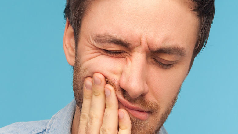 Man holding his jaw in discomfort