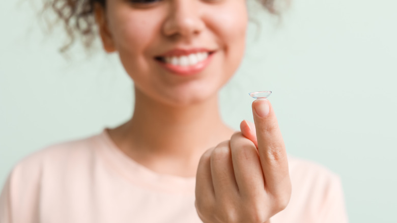 African-American woman holding contact lens