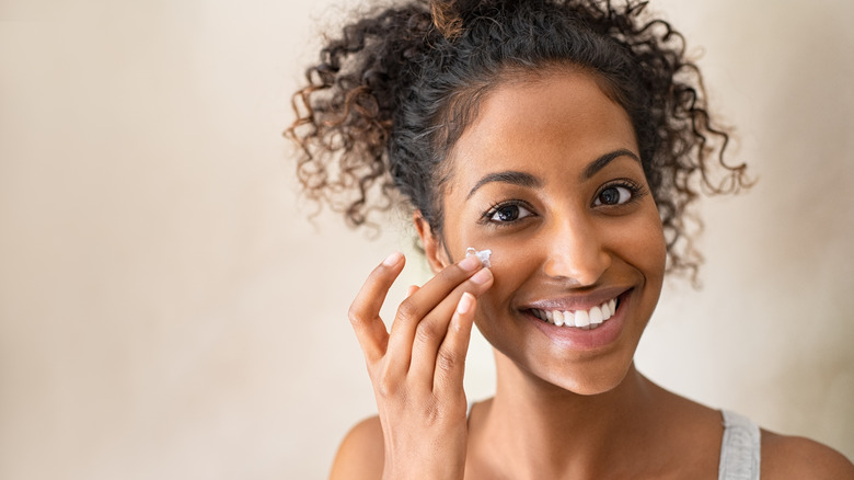 Woman dabbing moisturizer on cheek