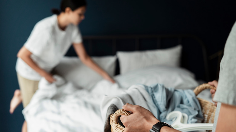Couple holding laundry and removing bed sheets