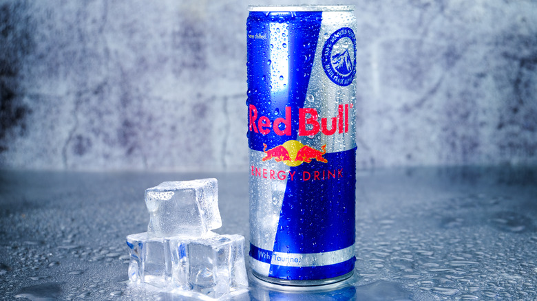 A can of Red Bull next to a pile of ice cubes