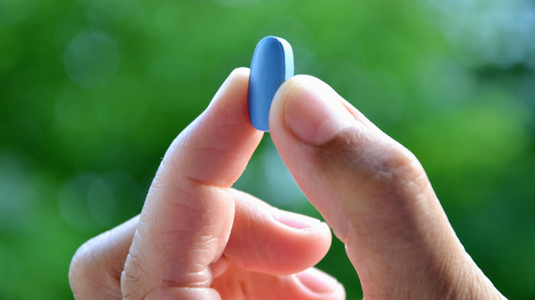 male hand holding up a Viagra 