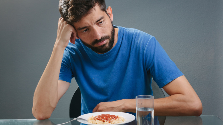 Man leaning head into fist at meal