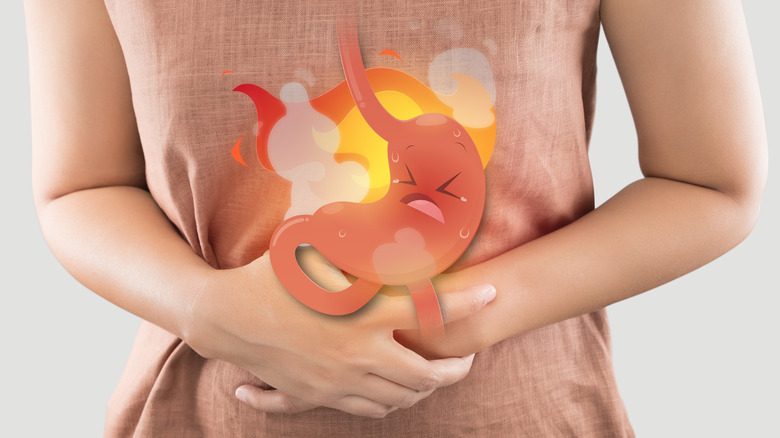 Woman clutching her stomach with cartoon graphic of stomach on fire