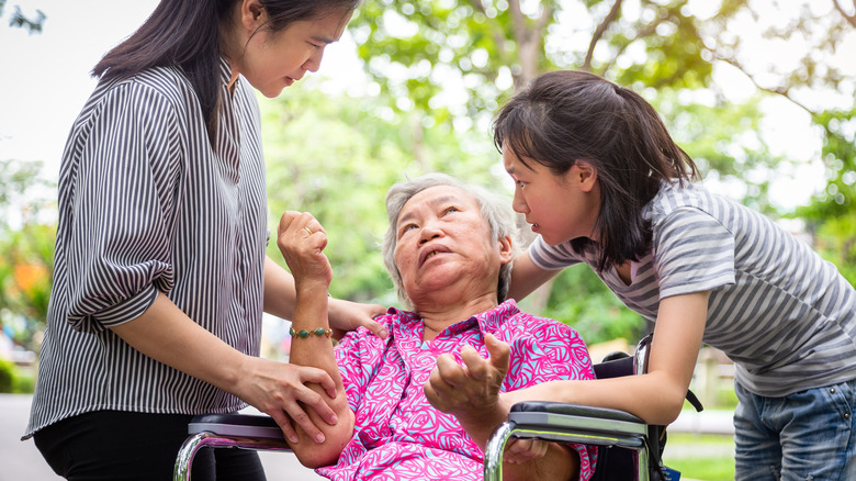 Elderly woman in wheelchair experiences a seizure with two young girls by her side