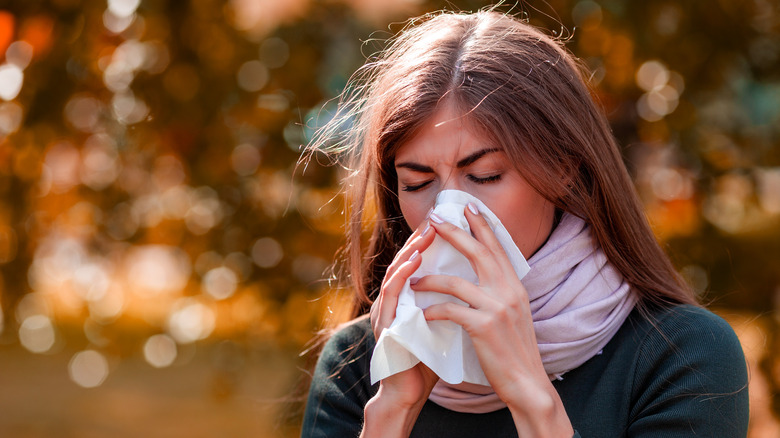 Woman sneezing outside