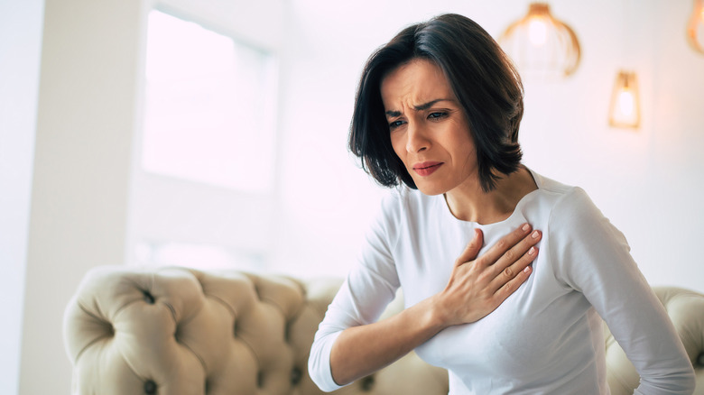 woman holding chest in pain