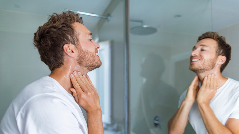 A man looking at his skin in the mirror