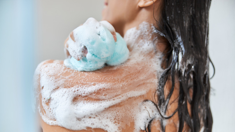 Woman showering with blue loofah