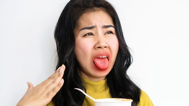 A woman fanning her tongue after eating hot food