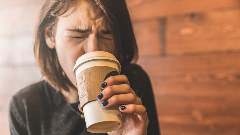 Woman drinking a cup of coffee that is too hot