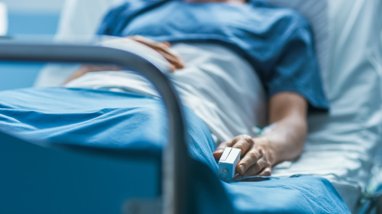 a person lying in a hospital bed with a heart monitor attached