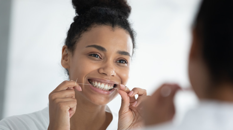 A woman flosses her teeth