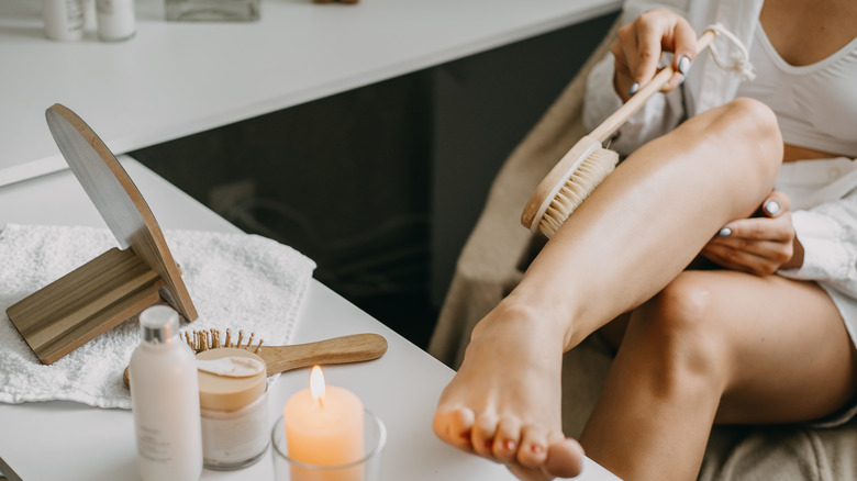 Woman is dry brushing to exfoliate her skin