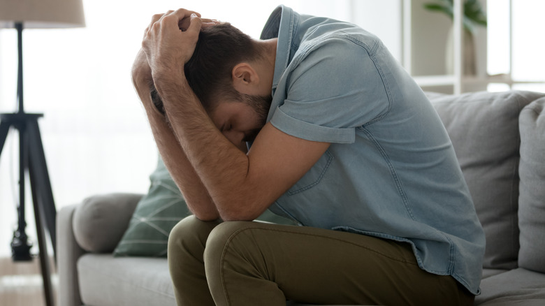 Man sitting holding his head