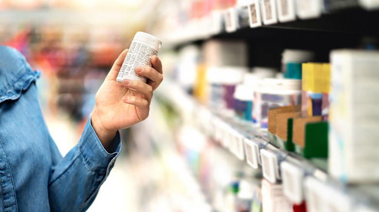 A person holding a bottle of vitamins in a store