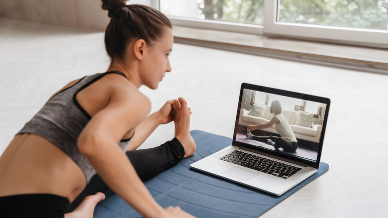 Young woman stretching while watching a virtual class