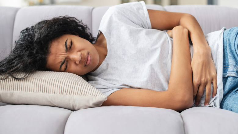 Woman laying on couch gripping belly