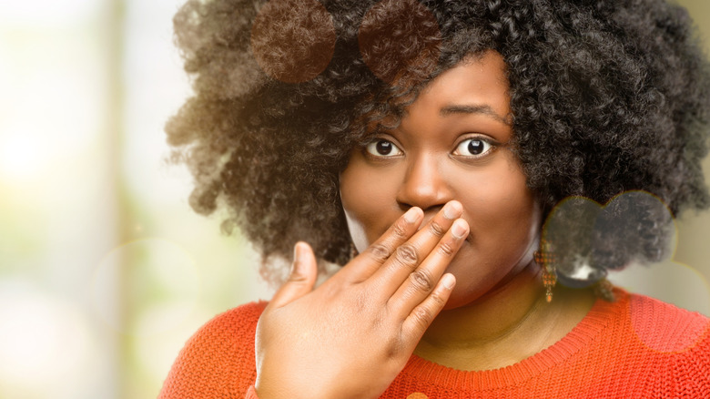 Embarrassed woman covering her mouth