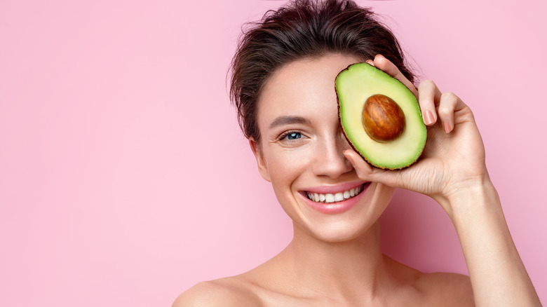 woman holding avocado over eye
