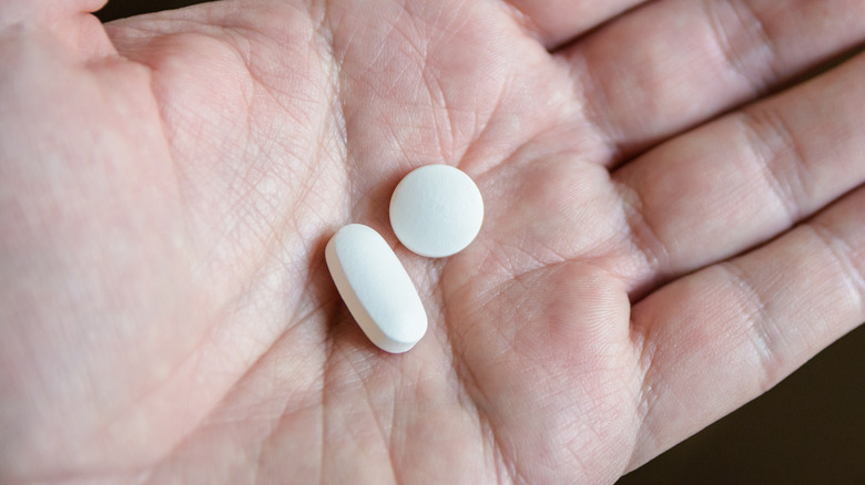 Person's hand holding two pills