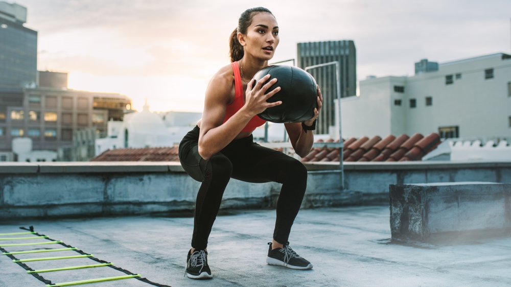 Woman squatting with medicine ball