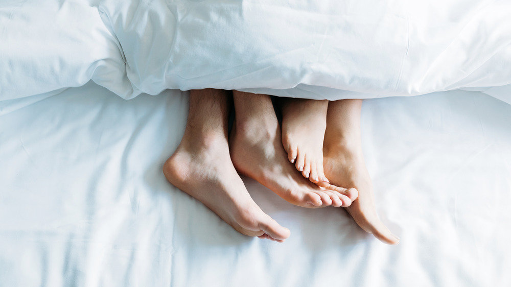woman and man with feet hanging out of blanket