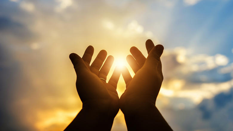 Outstretched hands against sky backdrop