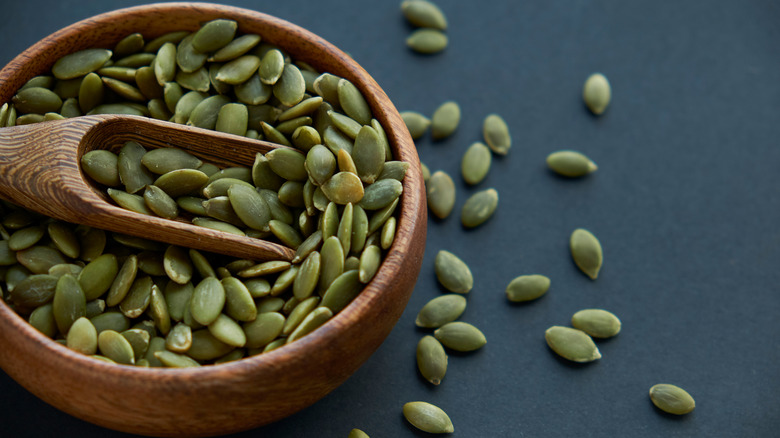 Wooden bowl and scoop full of pumpkin seeds