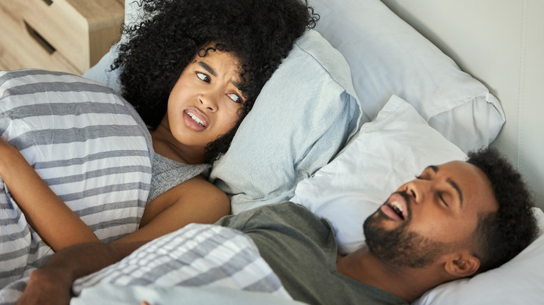 A woman awake in bed due to her snoring husband
