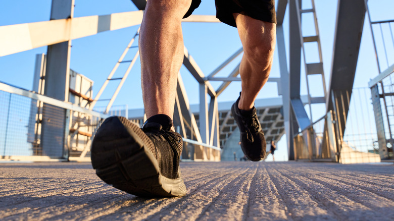 Close-up of a man's feet walking on a bridge
