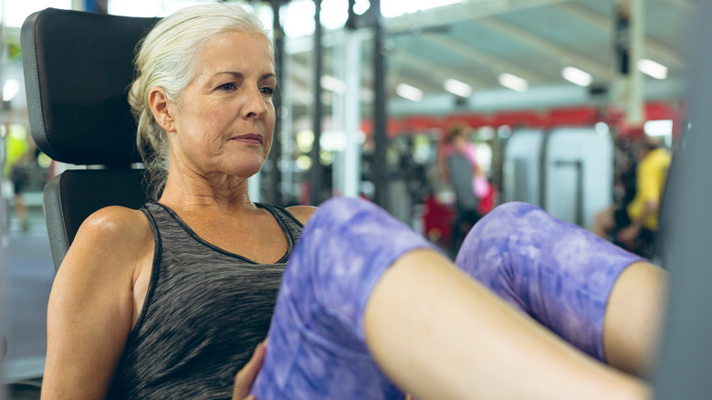 woman exercising with leg press machine in fitness studio