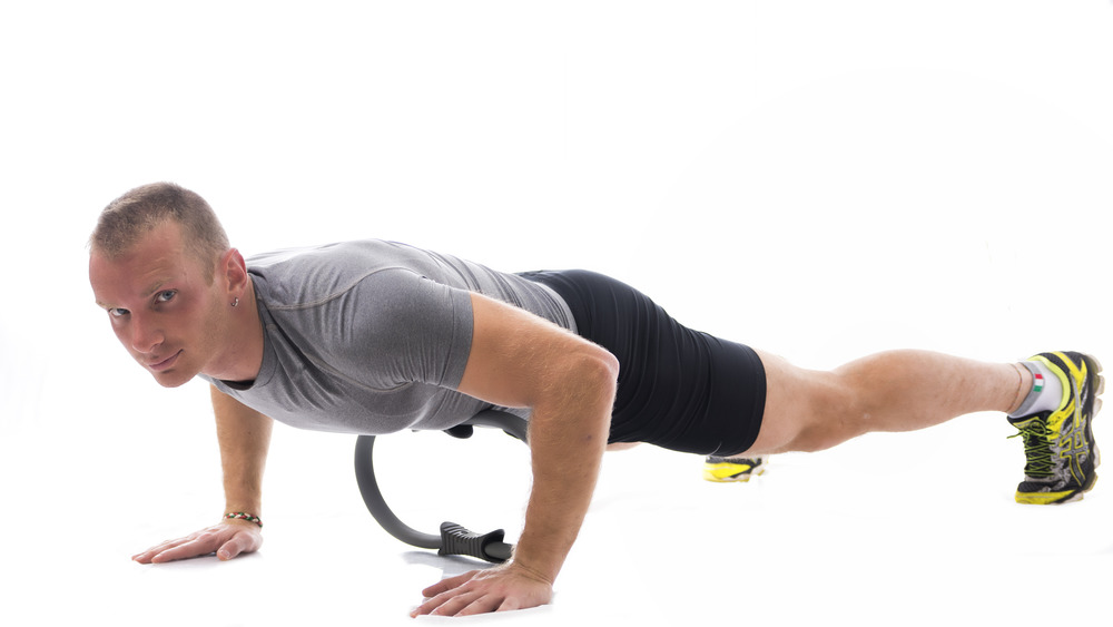 Man doing push ups with Pilates ring 