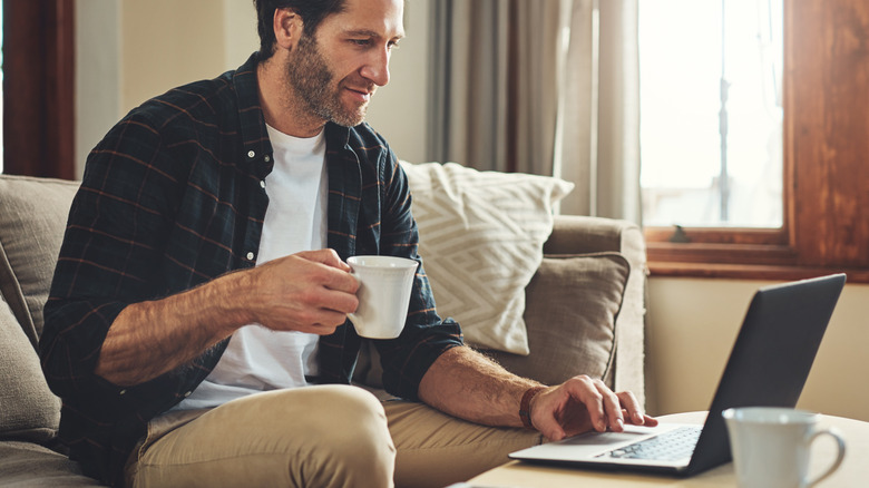 man drinking coffee while on his laptop