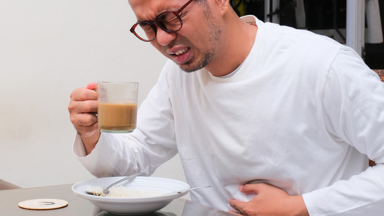 man drinking coffee and experiencing heartburn pain