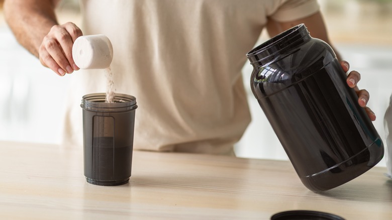 muscular man scooping protein powder