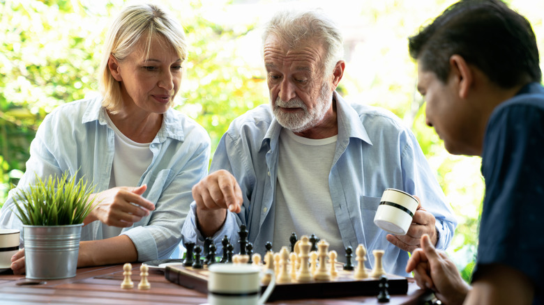 older man playing chess outdoors