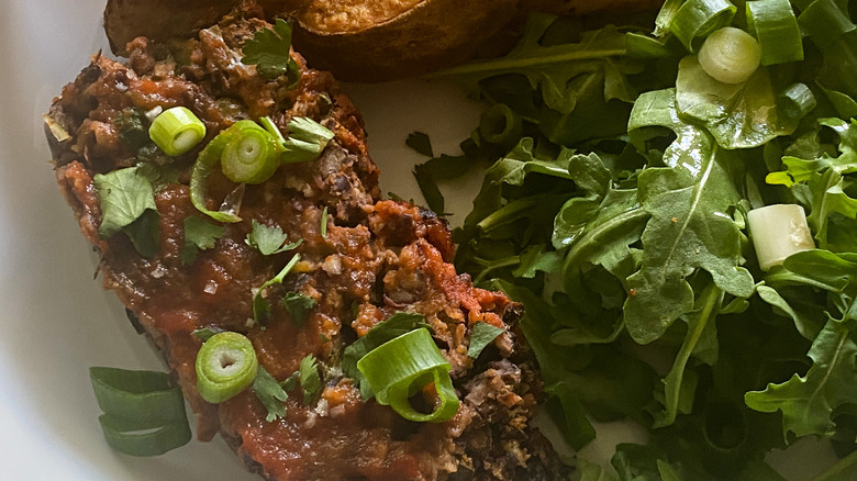 close up of vegetarian meatloaf with side of arugula