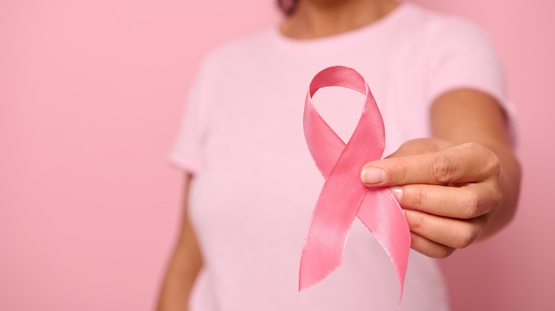 A woman holds a breast cancer ribbon