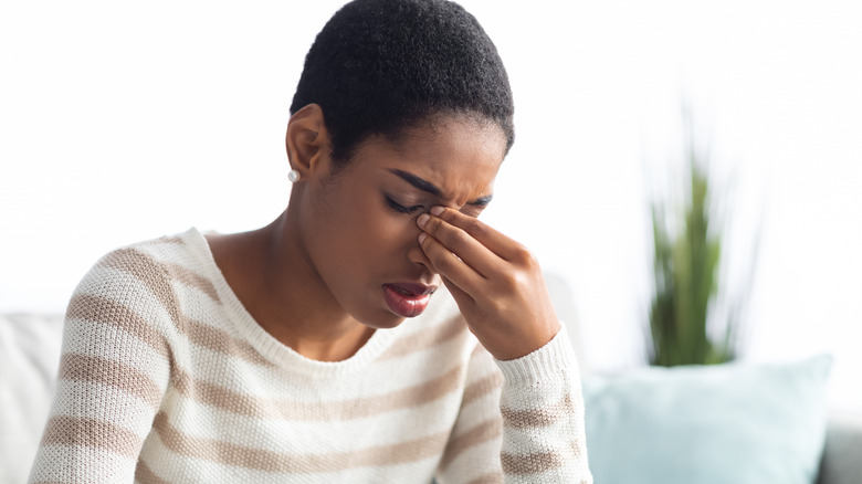 woman with sinus pressure squeezing her nose 