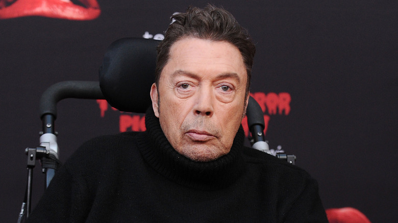 Tim Curry wearing black and posing at a screening event